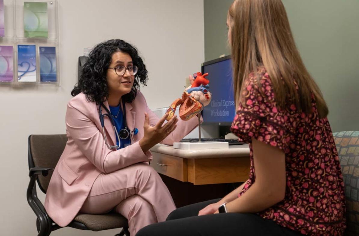 Mayo clinician and a student looking at a model heart in an office 