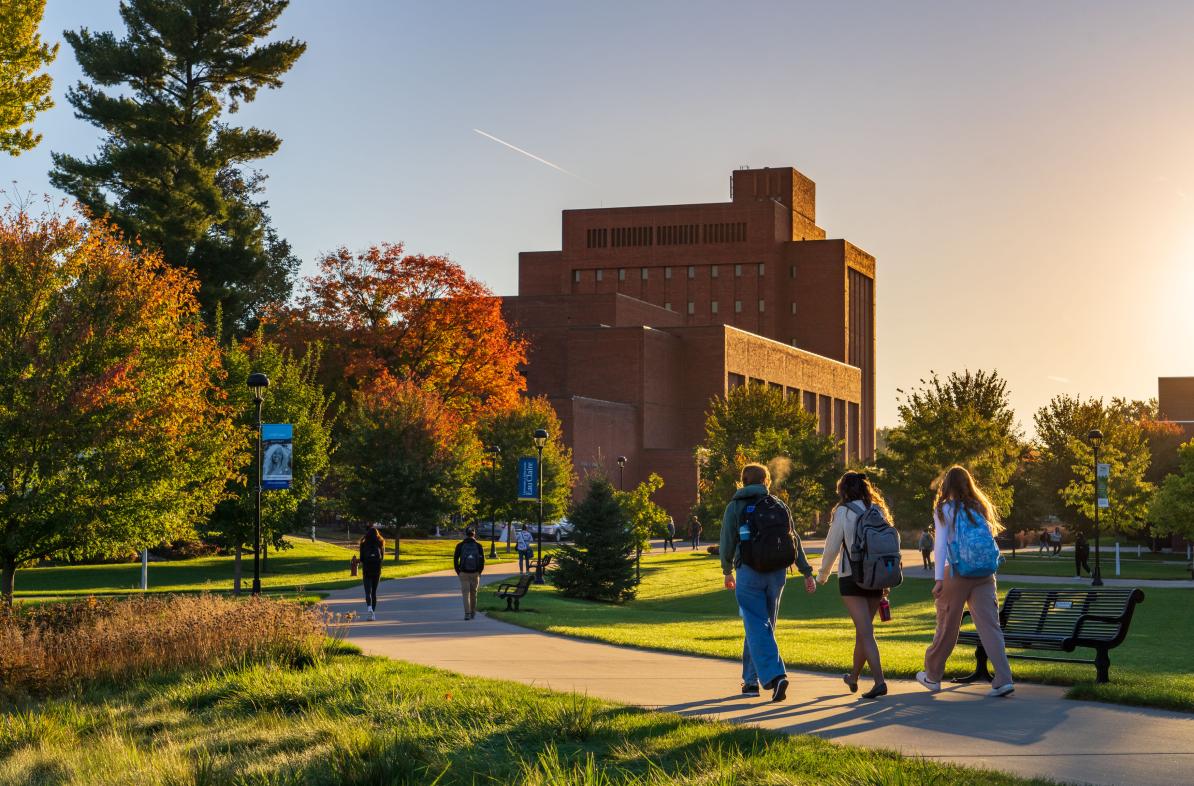 Students walk across campus as the fall sun sets.