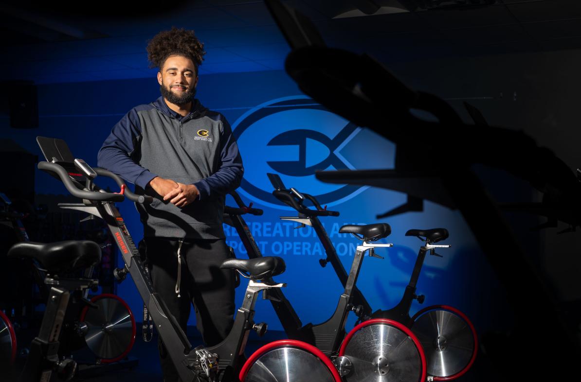 student recreation staff person in cycle studio leaning on a bike 