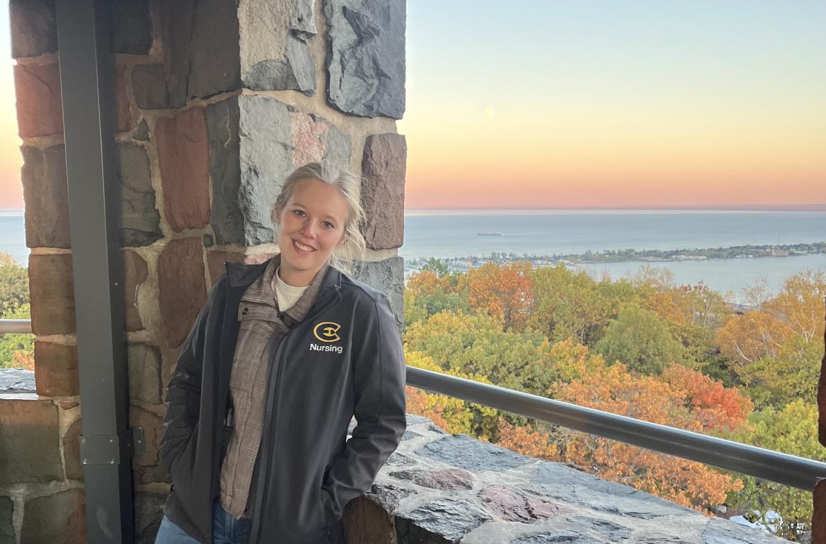 Adrianna Dahlberg stands in front of an autumn scene.