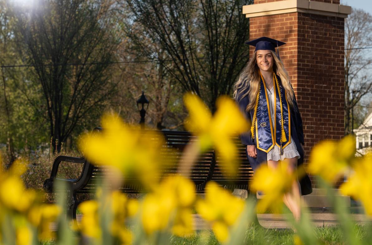 student in cap and gown near archway
