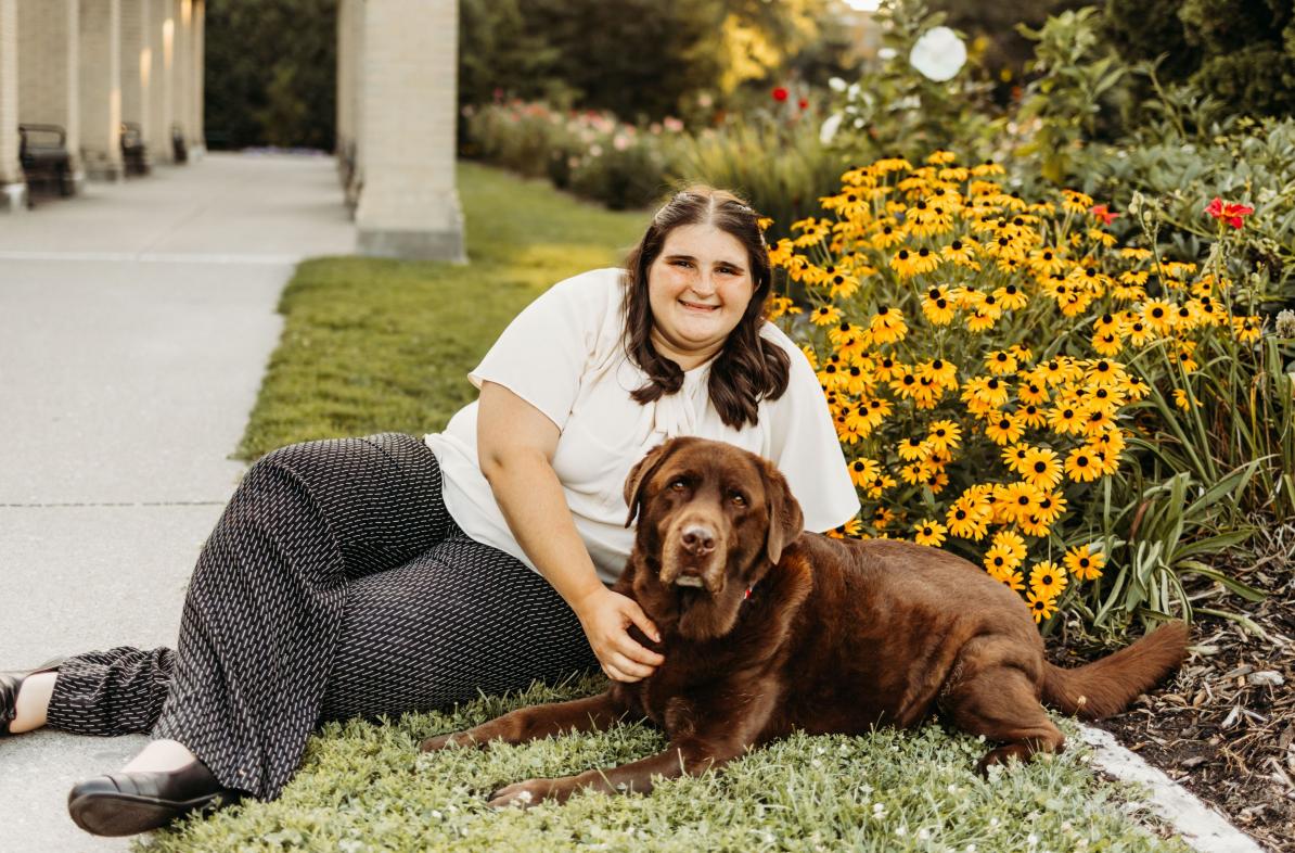 Megan Eilers lays in grass with her dog, Koda