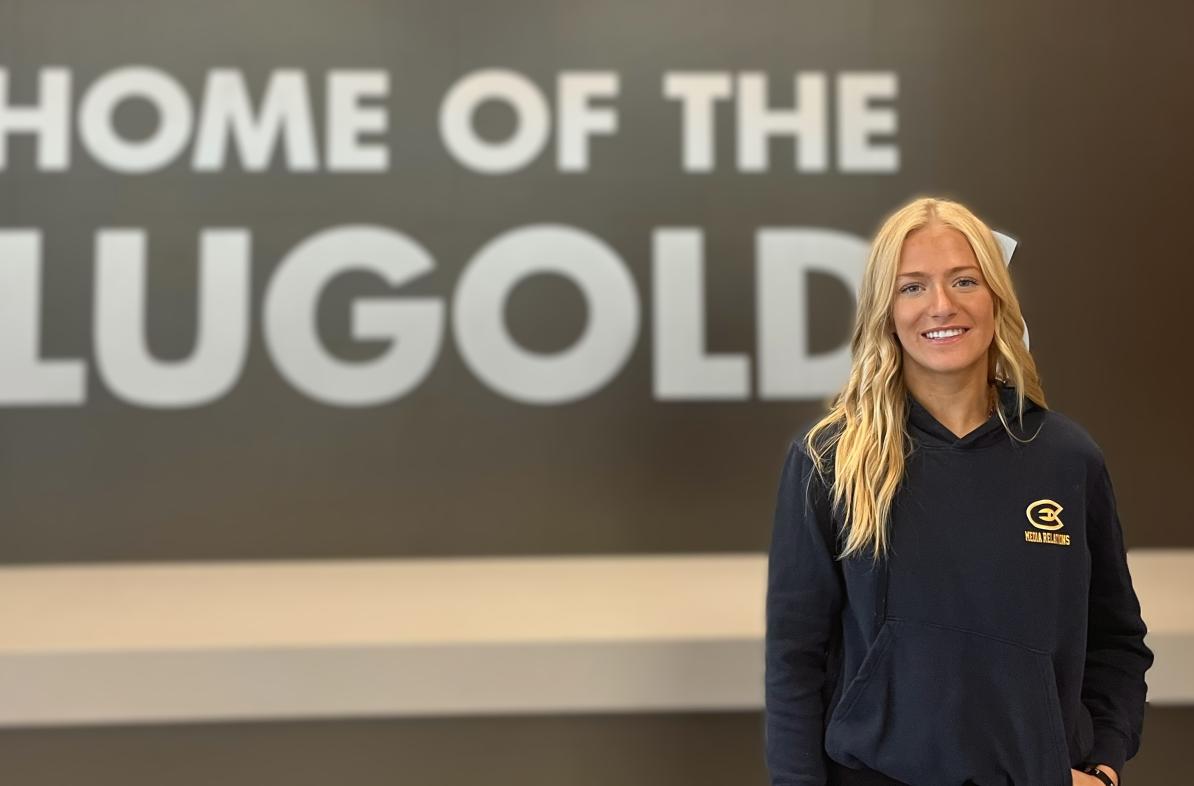 UWEC student Sydney Hoffman stands in front of the UWEC Home of the Blugolds sign