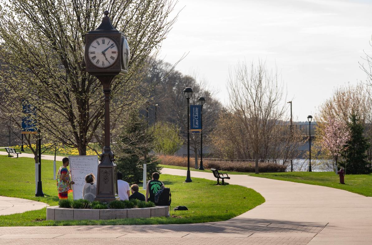 An outdoor class takes place under the clock tower on campus