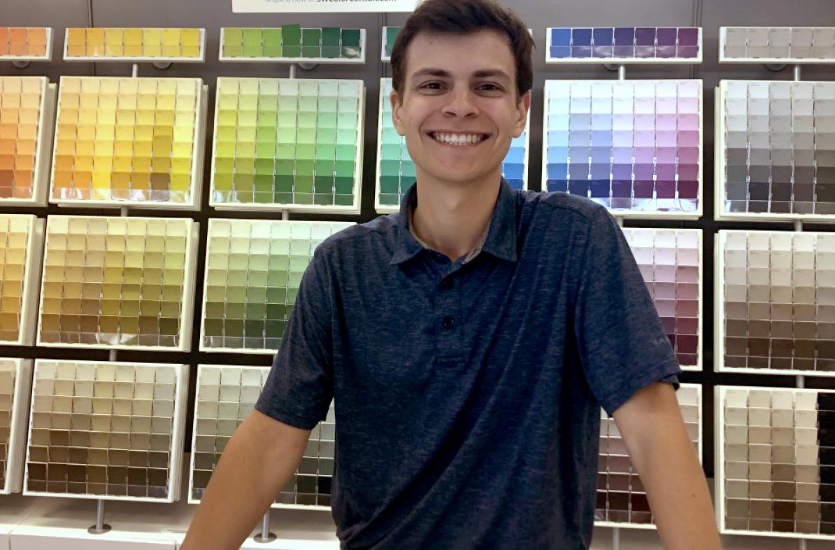male student standing at counter in paint store