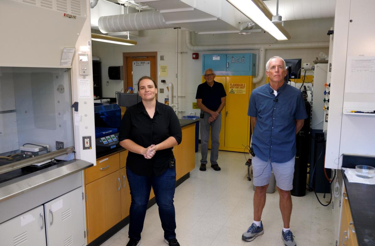 three faculty, two men nd one woman, in a chemistry lab