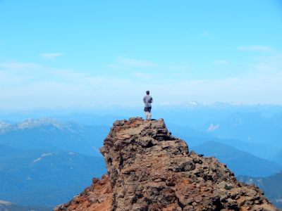 A student on a study abroad program in Chile, Valparaiso, standing on top of the rocky peak with an amazing scenario of blue sky and mountains 