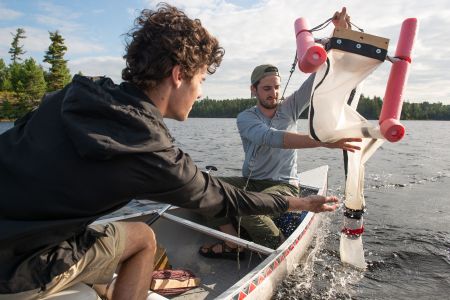 Two students in a canoe conducting an experiment on a lake for sustainability