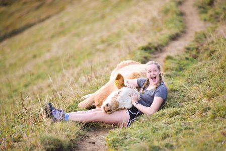 A student during study aboard in Sweden lying in the grass cuddling a cow