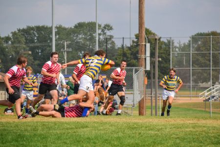 Two rugby teams chase each other on the pitch.