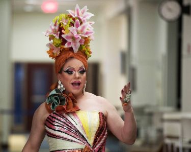 A drag performer gestures to the camera. 