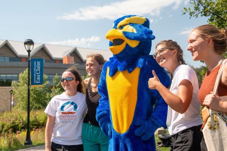 Blu taking a photo with a group of students smiling.