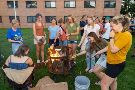 Group of students gathered around a campfire.