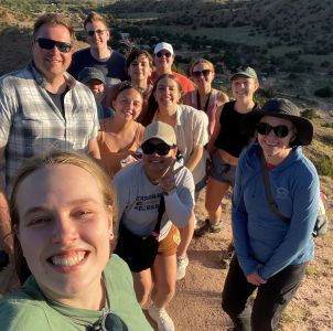 New Mexico immersion students and faculty leaders group for a selfie at the top of a rocky hike.
