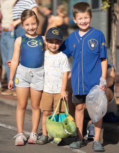 Three kids smile at the camera holding bags of candy during the 2025 Homecoming game.