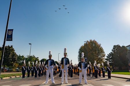 The Blugold Marching Band poses while airplanes fly overhead during the Homecoming parade.