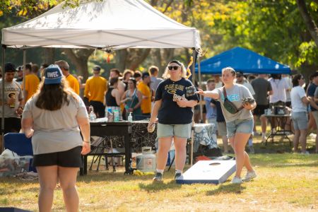 Students play bags while tailgating before the 2025 Homecoming game.