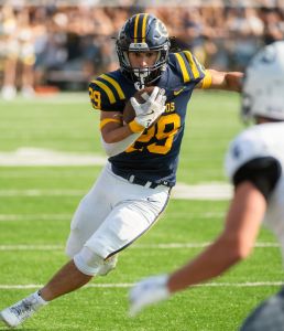 Blugold football player runs while holding the ball during the 2025 Homecoming game