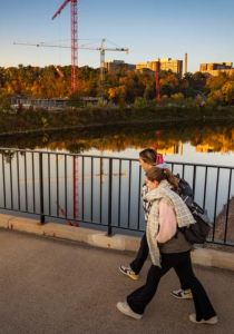 Fall colors surround the new Science and Health Sciences Building as two students walk across the bridge nearby.