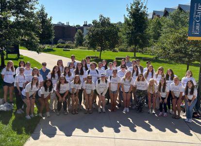 Honors 410 mentors in matching tees pose outside in rows for a group photo 