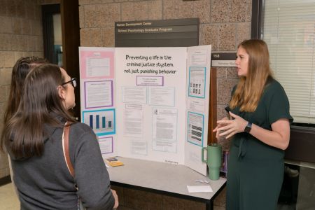 A Social Work student presents her poster board to another individual.