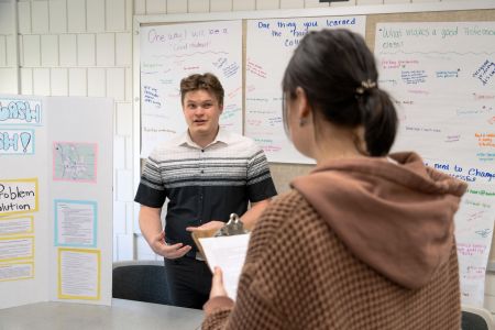 Social Work students collaborate together surrounded by white posterboards with written notes and ideas.