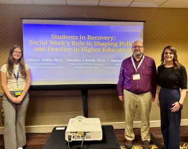 Social Work students stand by a projector during a presentation.