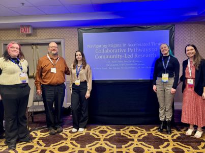 Social Work students and professors stand in front of a projected image.