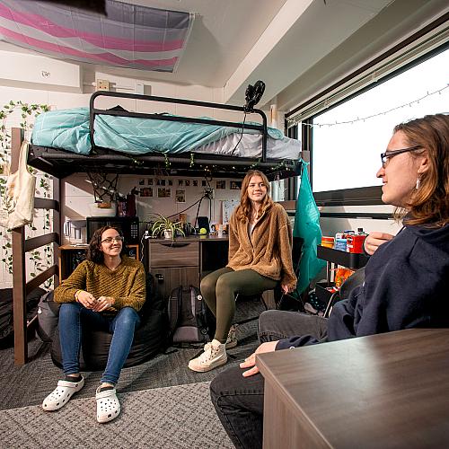 Students sitting and talking in a residence hall room.