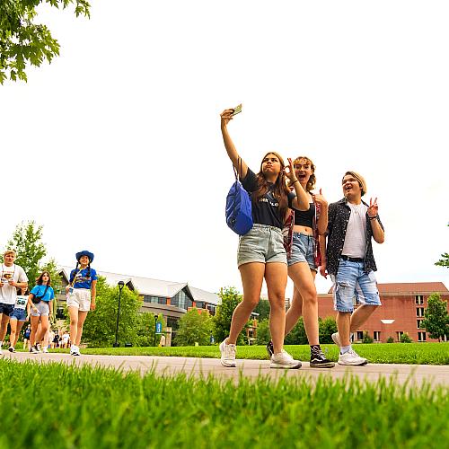 three visiting students taking a selfie on the mall sidewalk 