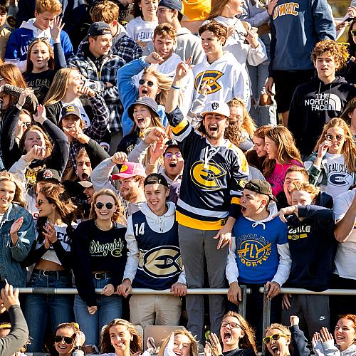 A crows of UWEC students at sport event with an excitedly cheering.
