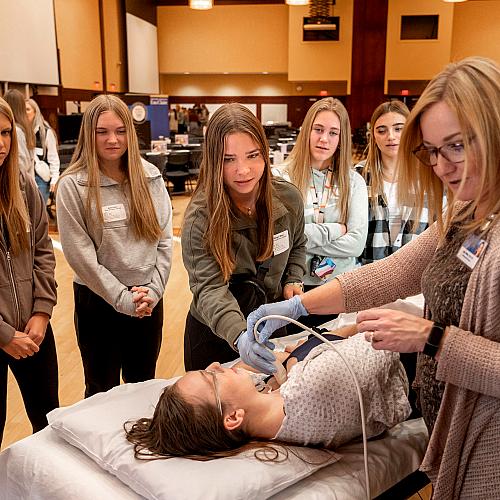 A group of students observing a healthcare demonstration