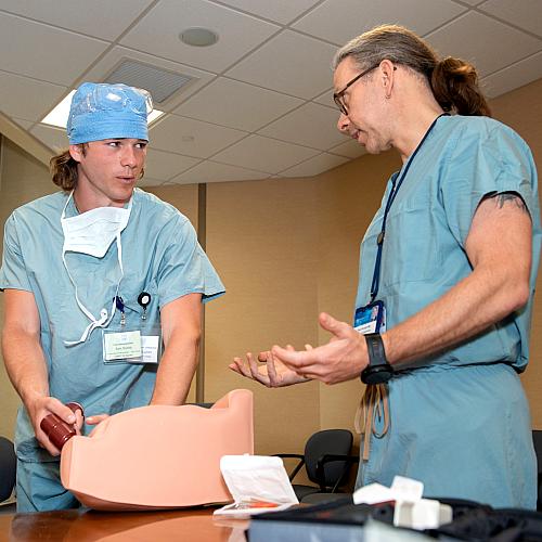 A student works on a simulation with a Mayo Clinic physician, both wearing scrubs.