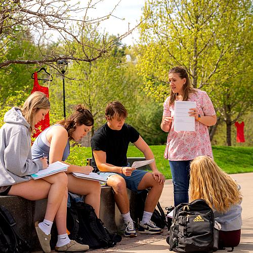 Students in a math class learn from a professor in an outdoor classroom area