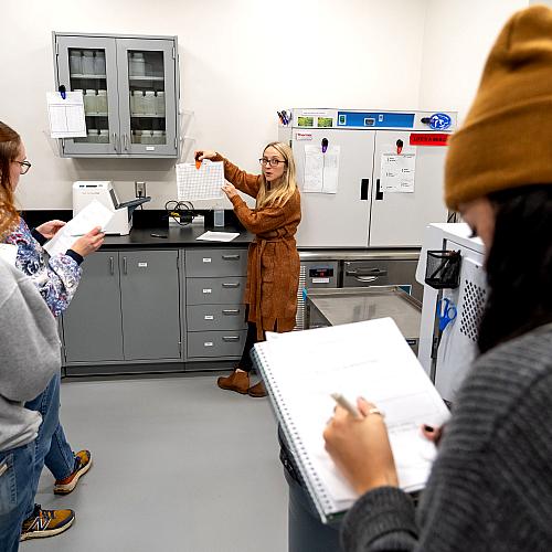 Student writes on a notepad during a lab visit for the Environmental Public Health program.