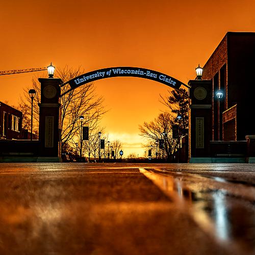 UWEC Archway in front of a dark orange sunset. 