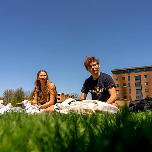 Two students study in the grass on the campus mall.