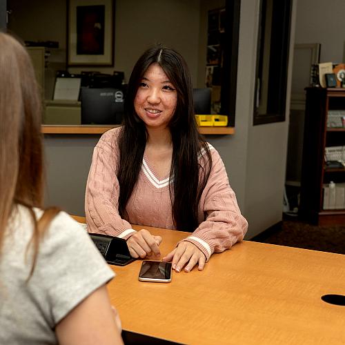 Student smiles at another student while sitting across from one another
