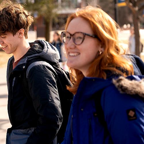 Students smile as they walk across campus on a winter morning.