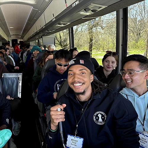 A student smiles at the camera while on the bus during the Civil Rights Pilgrimage.