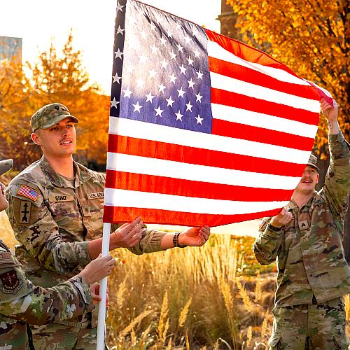Flags being installed for Veterans Day by three military students 