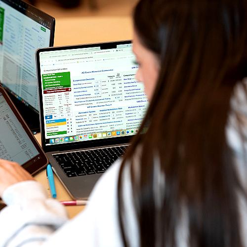 A student looks at a laptop while gathered for the College of Business SIM Super Bowl