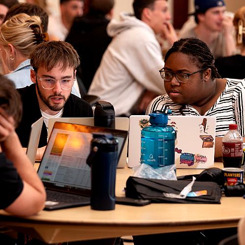 Students look at a laptop while gathered for the College of Business SIM Super Bowl
