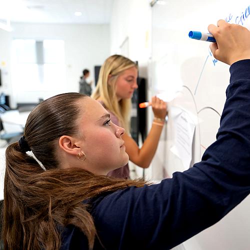 A student writes on a white board during Orientation.