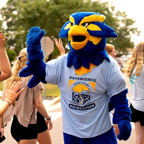 Blu wearing a tshirt high-fives students.
