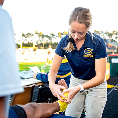 Student taping an ankle during a UWEC soccer game
